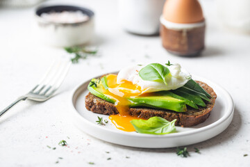 Healthy breakfast whole wheat toasted bread with avocado and poached egg over white background