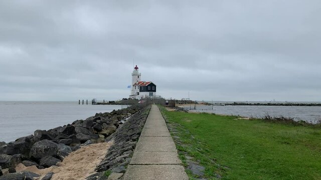 Path going to the  white Marken town lighthouse (The Paard van Marken) surrounded by waving water.  It is build on Marken peninsula on the Lake Ĳssel (IJsselmeer). Marken, North Holland, Netherlands