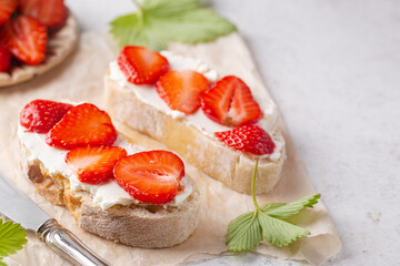 Strawberries sandwiches with cream cheese and on paper, light background