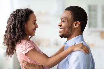 Black little girl and father hugging, looking at each other
