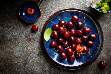 Fresh ripe cherry on blue plate top view with copy space
