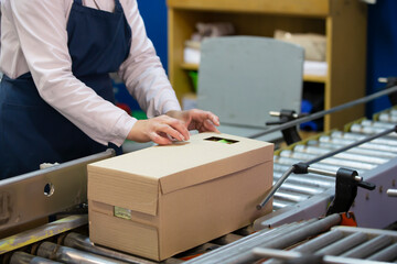Packing conveyor. The hands of the packer pack the goods into the box.