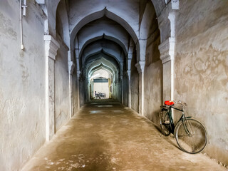 Fototapeta na wymiar A bicycle parked in a long arcaded corridor inside the ancient Maratha Palace in Thanjavur.