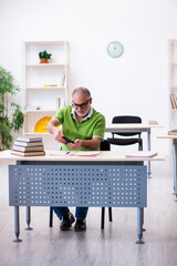 Old male student preparing for exams in the classroom