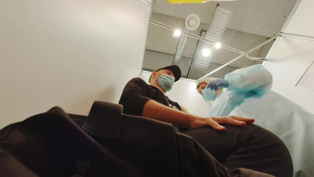 Siauliai, Lithuania - 3rd, June, 2021: Young person get shot Pfizer vaccine in vaccination cabin isolated by nurse. Vaccination in Lithuania, Europe.