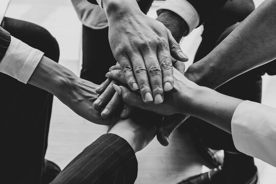 close up picture of hands of multiethnic business team touching in circle for sign of unity and integrity. monochrome