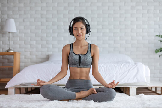 Wellness Asian indian woman wearing headphone to coaching in yoga class streaming online at home,Healthy young woman Exercise training hatha yoga Self isolation workout,New normal of yoga concept