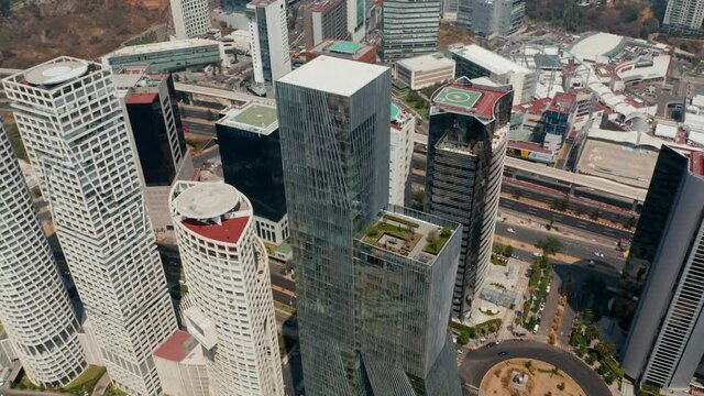 Aerial drone view of Paradox Torre building and surrounding skyscrapers. Tall modern business towers. Camera tilting up to show cityscape. Mexico city, Mexico.