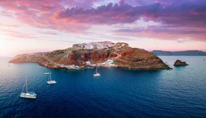 Panoramic aerial view to the villages of Oia and Ammoudi surrounded by the steep, volcanic rock...