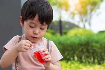 Cute little child love eating sweets or snack. Handsome little boy enjoy eating gelatin or jelly. Adorable kid like eating snack. He feel happy when he eat favorite sweet with garden background - obrazy, fototapety, plakaty