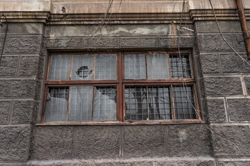 big dirty broken window. dark wall of a large house. Vintage architecture classical facade old gray building front view