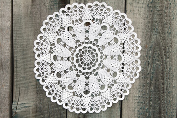 Beautiful crochet doily on old wooden background