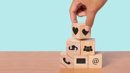 Hand arranging wood block with icon contact. Customer service mind concept.