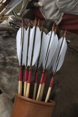 Leather bow quiver filled with arrows with graven woodnock and traditional natural fletching as archery concept.
