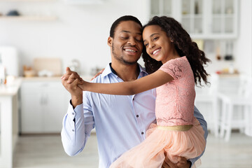 Emotional black father and daughter dancing waltz at home