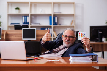 Old male employee playing cards at workplace
