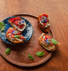 Strawberry toast brioche with cream cheese decorated with flowers and basil fflat lay close up