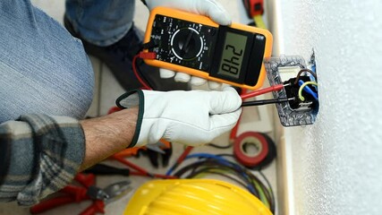 View from above. Electrician worker at work with the tester measures the voltage in an electrical system. Working safely with protective gloves. Construction industry. Footage.