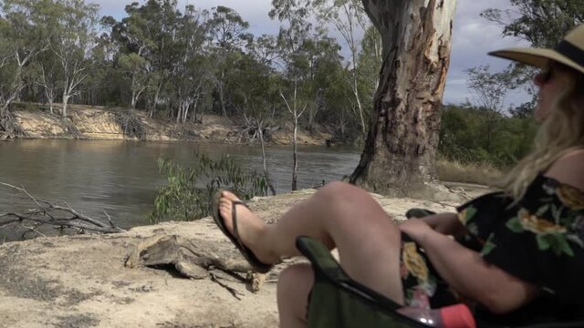 Outdoor nature blonde woman comes over and sits on camping chair Australian summer