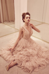 Young lady white caucasian woman with hairstyle in rose pink wedding dress posing on a pink classic sofa - 437727267