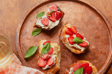 Strawberry toast brioche with cream cheese decorated with flowers and basil fflat lay close up