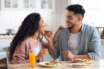 Happy young arab couple enjoying eating their breakfast together at home