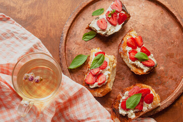 Strawberry toast brioche with cream cheese decorated with flowers and basil fflat lay close up