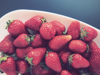Strawberries on a plate, gray background. White dishes and delicious red large garden strawberries....