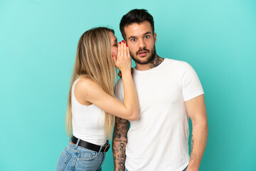 Young couple over isolated blue background whispering something