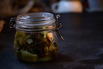 Pickled lettuce in glass jar on dark background