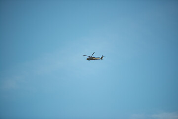 The helicopter flies in the blue sky on a summer day