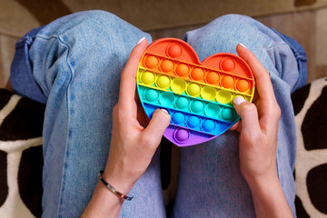 Colorful antistress sensory toy push pop it in girl hands.