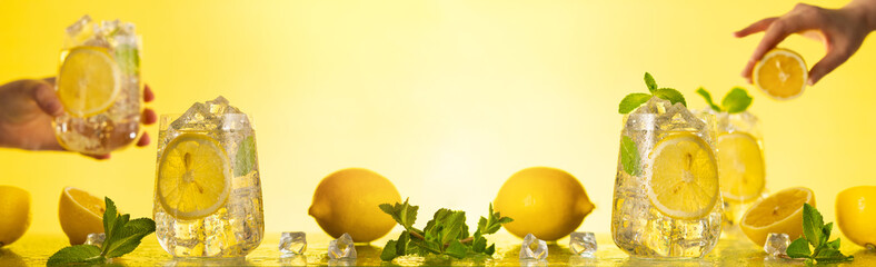 Lemonade with fresh slice lemon and mint leaves. Woman holding glass of lemonade. Summer homemade drink.