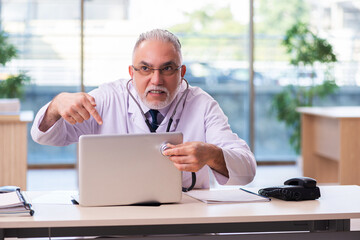 Old male doctor working in the clinic