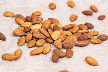 Raw almond nuts heap on light paper background.
