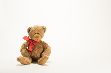 A toy teddy bear sitting on the white background with copy space.