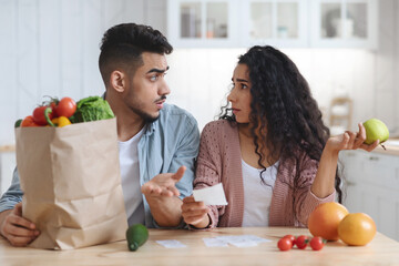 Prices Increase. Frustrated Young Arab Spouses Looking At Bills After Grocery Shopping