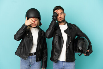 Couple with motorcycle helmet over isolated blue background with surprise and shocked facial expression