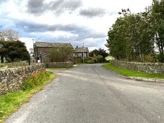 Looking along, Cross Wells Road, with dry stone walls, flowers, and cottages near, Ripponden, Yorkshire, UK