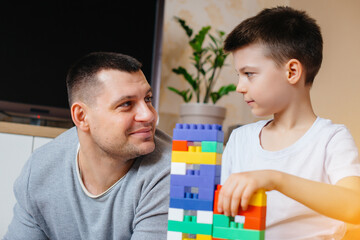 A little boy together with his father is played by a constructor and builds a house. Construction of a family home.