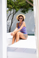 Fototapeta na wymiar Beautiful woman in swimsuit at backyard pool at summer sunny day enjoying amazing warm weather, catching sun rays