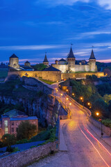 Fototapeta na wymiar Night view of illuminated Old Town and Kamianets-Podilskyi Castle, a medieval fortress featuring several original towers.