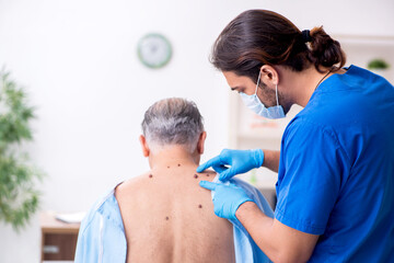 Old man visiting young male doctor dermatologist