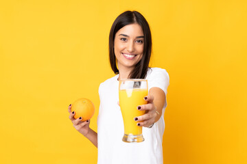 Young caucasian woman holding an orange over isolated yellow background