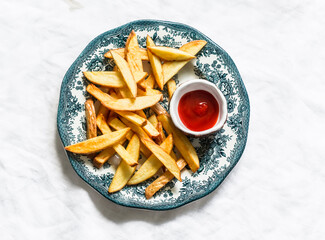 Fried French fries and ketchup on a light background, top view