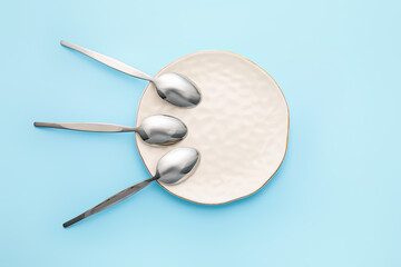 Clean spoons with plate on color background