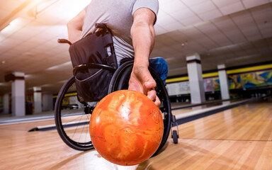 Young disabled man in wheelchair playing bowling in the club