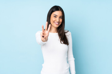 Young caucasian woman isolated on blue background happy and counting three with fingers - obrazy, fototapety, plakaty