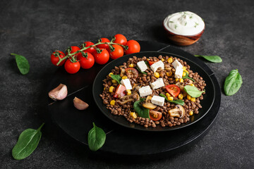 Plate with tasty cooked lentils, vegetables and cheese on dark background