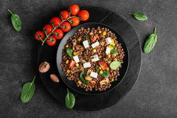Plate with tasty cooked lentils, vegetables and cheese on dark background